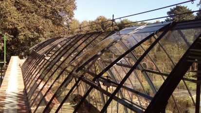 Une serre en ogive, partiellement adossée et toute en transparence, dans un joli jardin anglais
